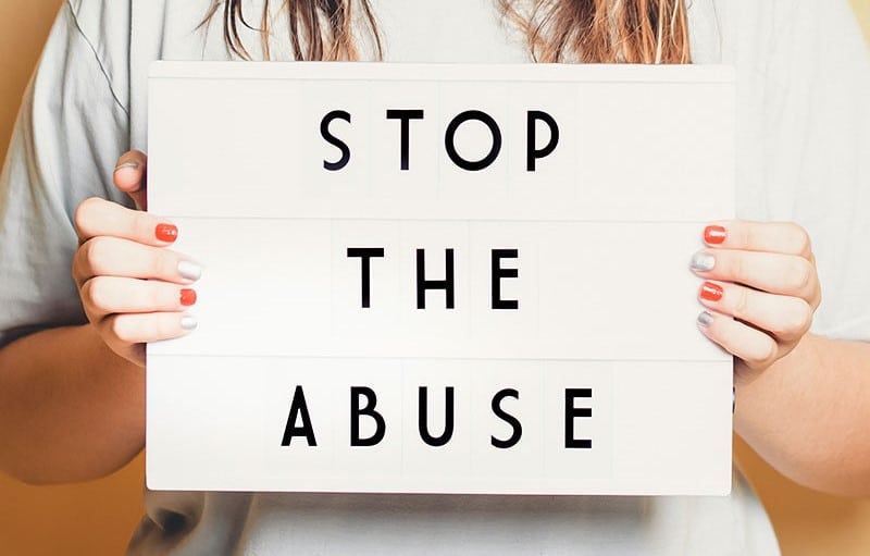 Woman holding up a light box with the words "stop the abuse",