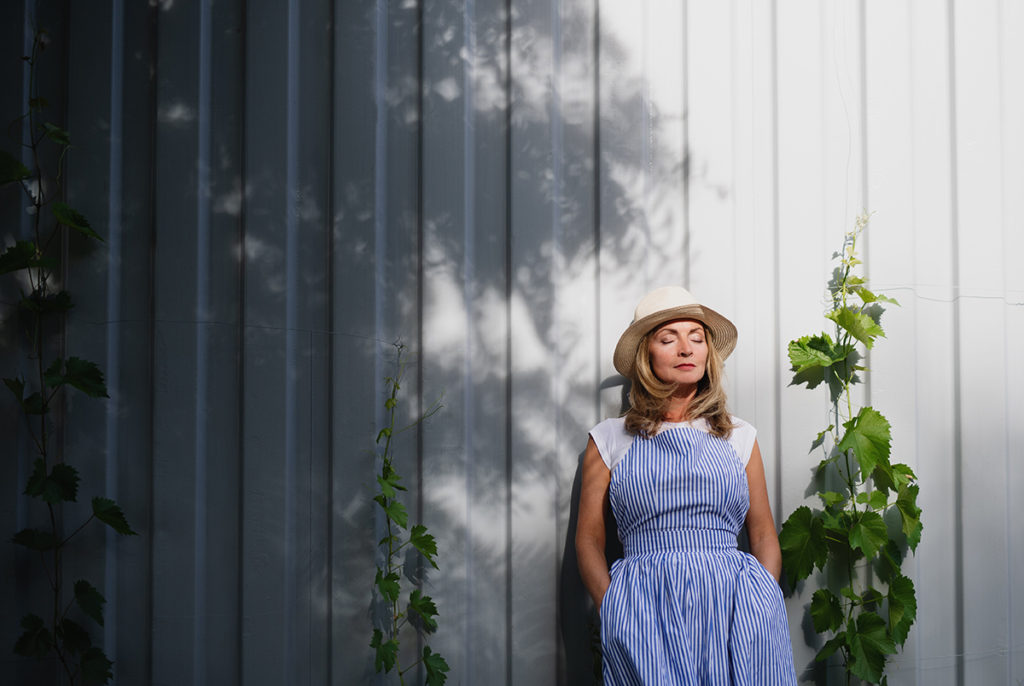 Portrait of mature woman standing outdoors in garden, relaxing with eyes closed.