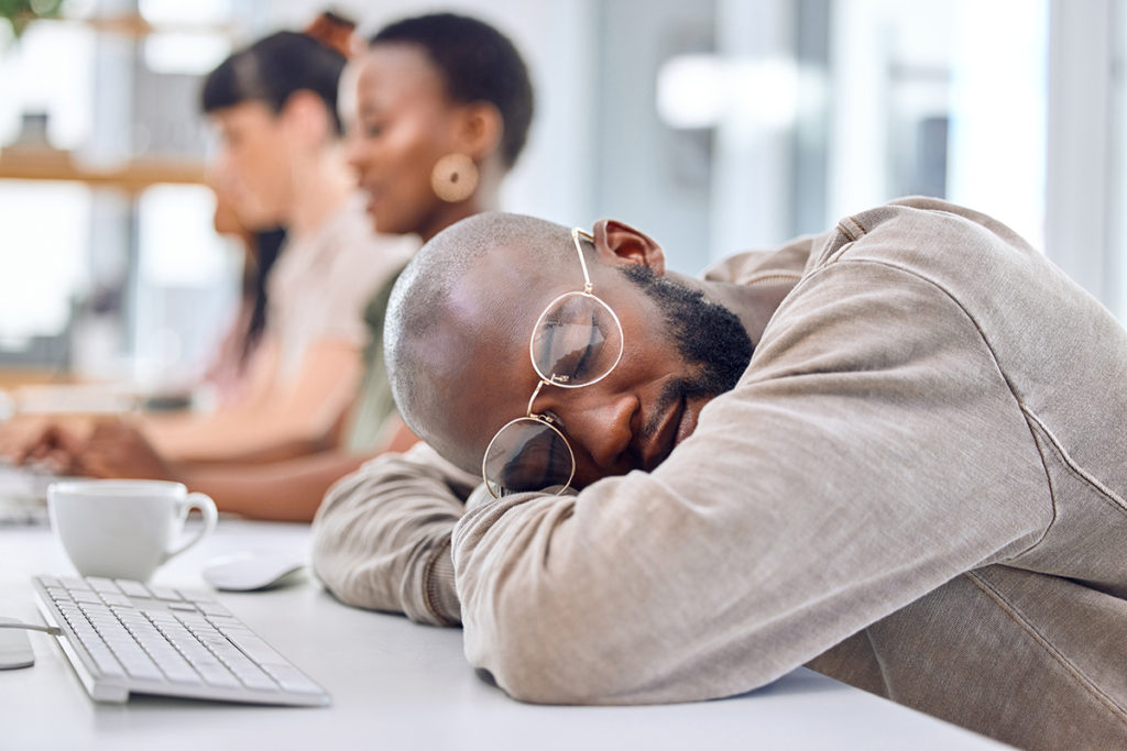 Shot of a young man sleeping at his desk in an office