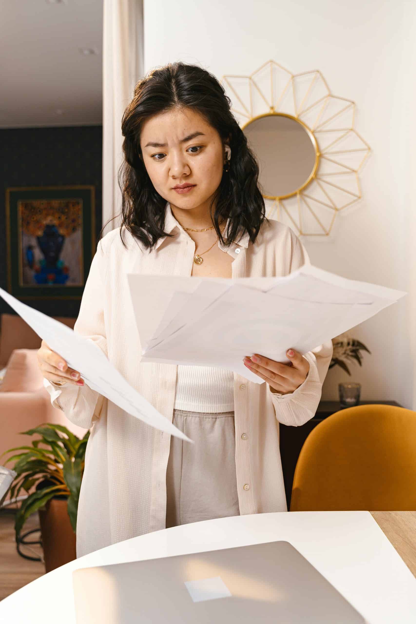 Woman looking confused at a stack of paperwork in her hands.